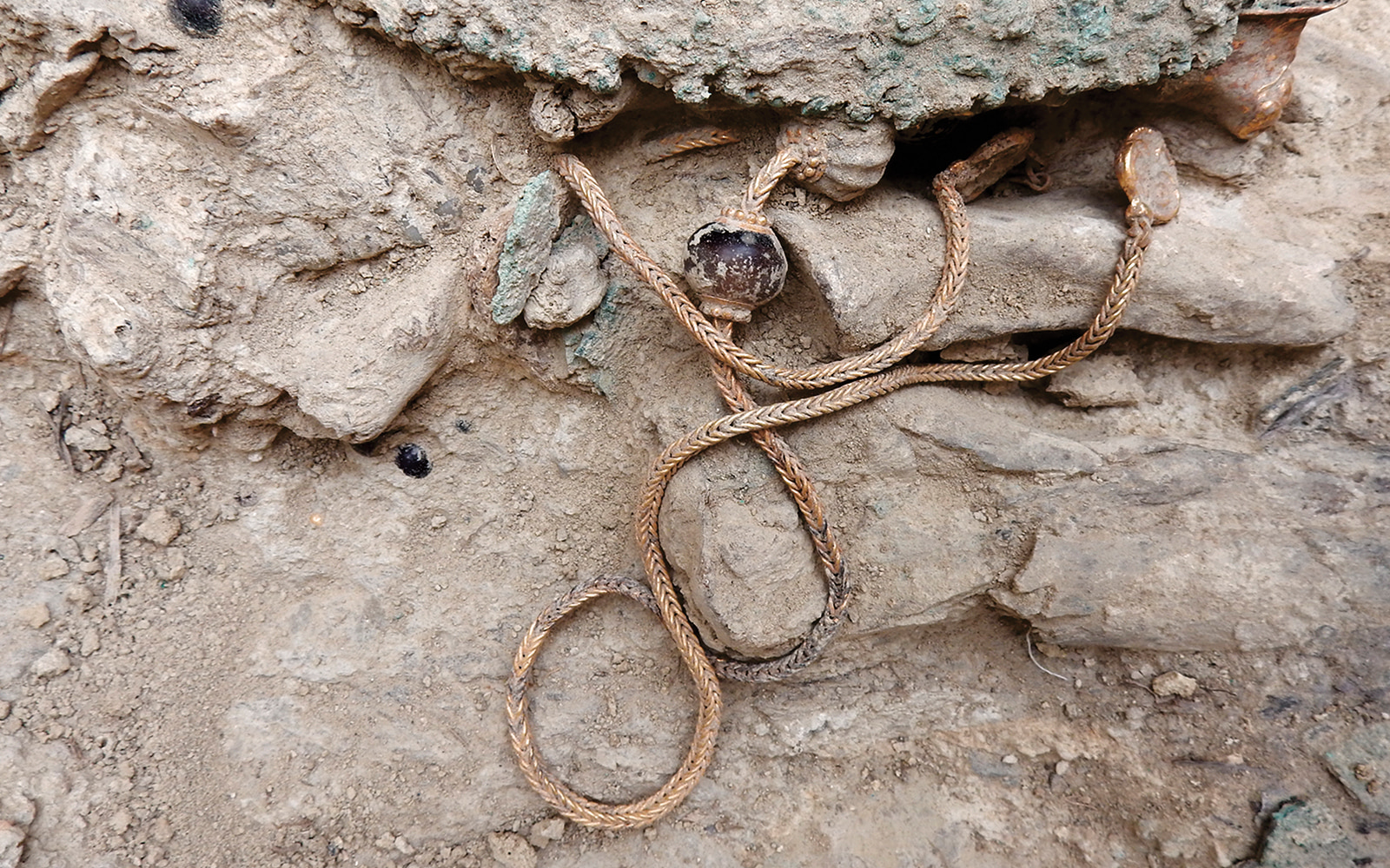 More treasures from the tomb: a gold necklace before removal (top).