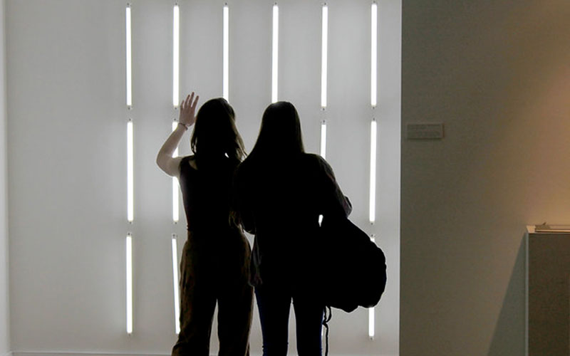 Two figures standing in front of strips of light