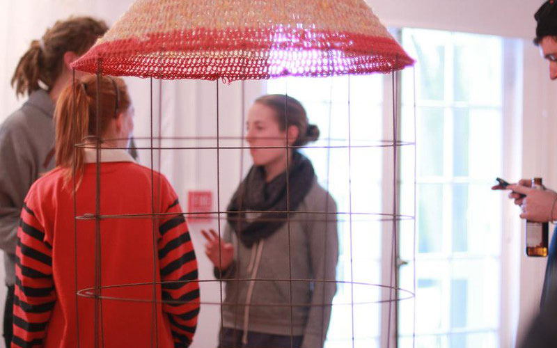 People seen through a sculpture hanging from ceiling