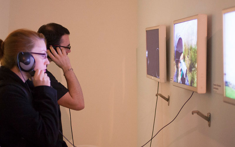 Two people with headphones on watching screens