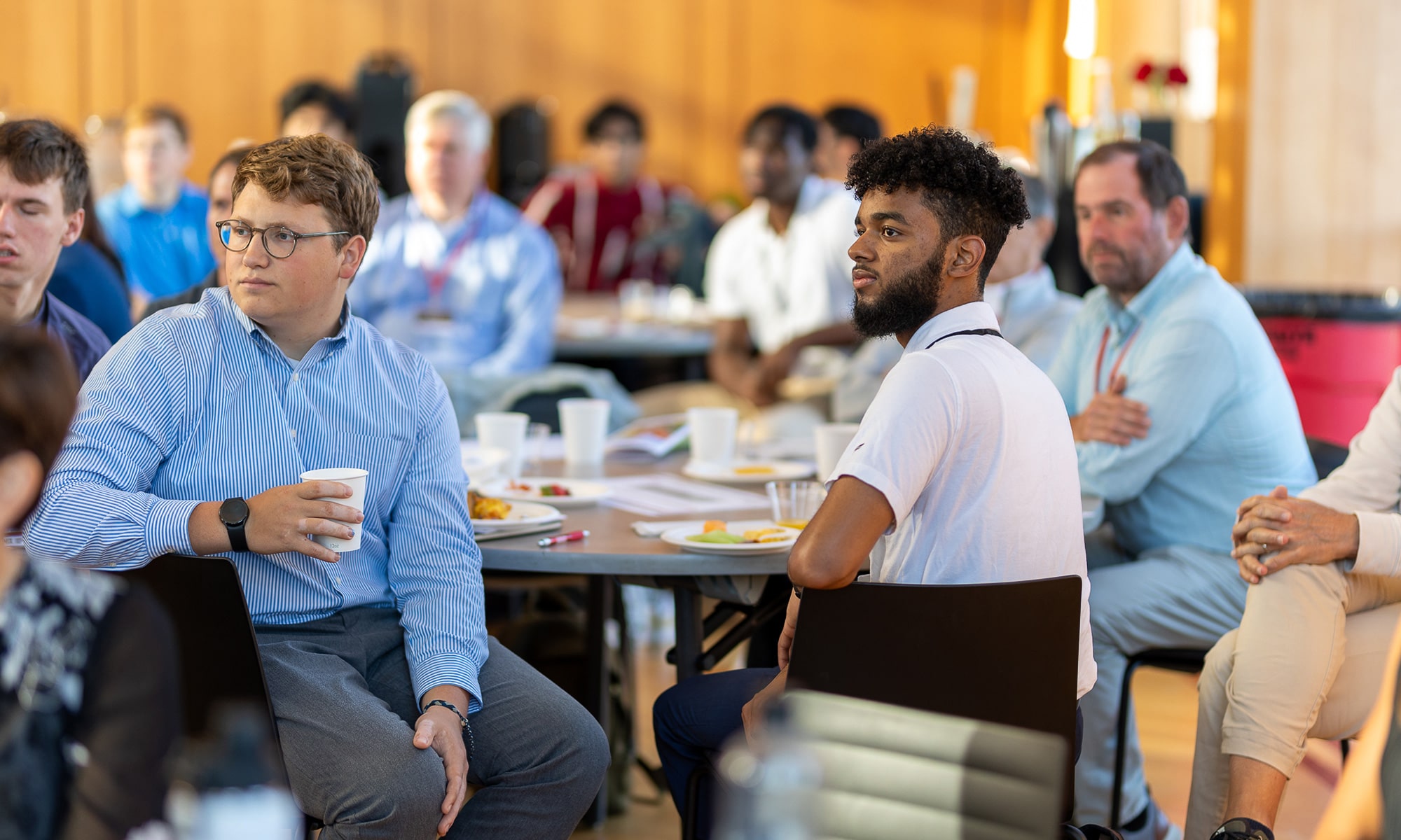 Members of the audience at ReMix sit around tables while listening to a speaker