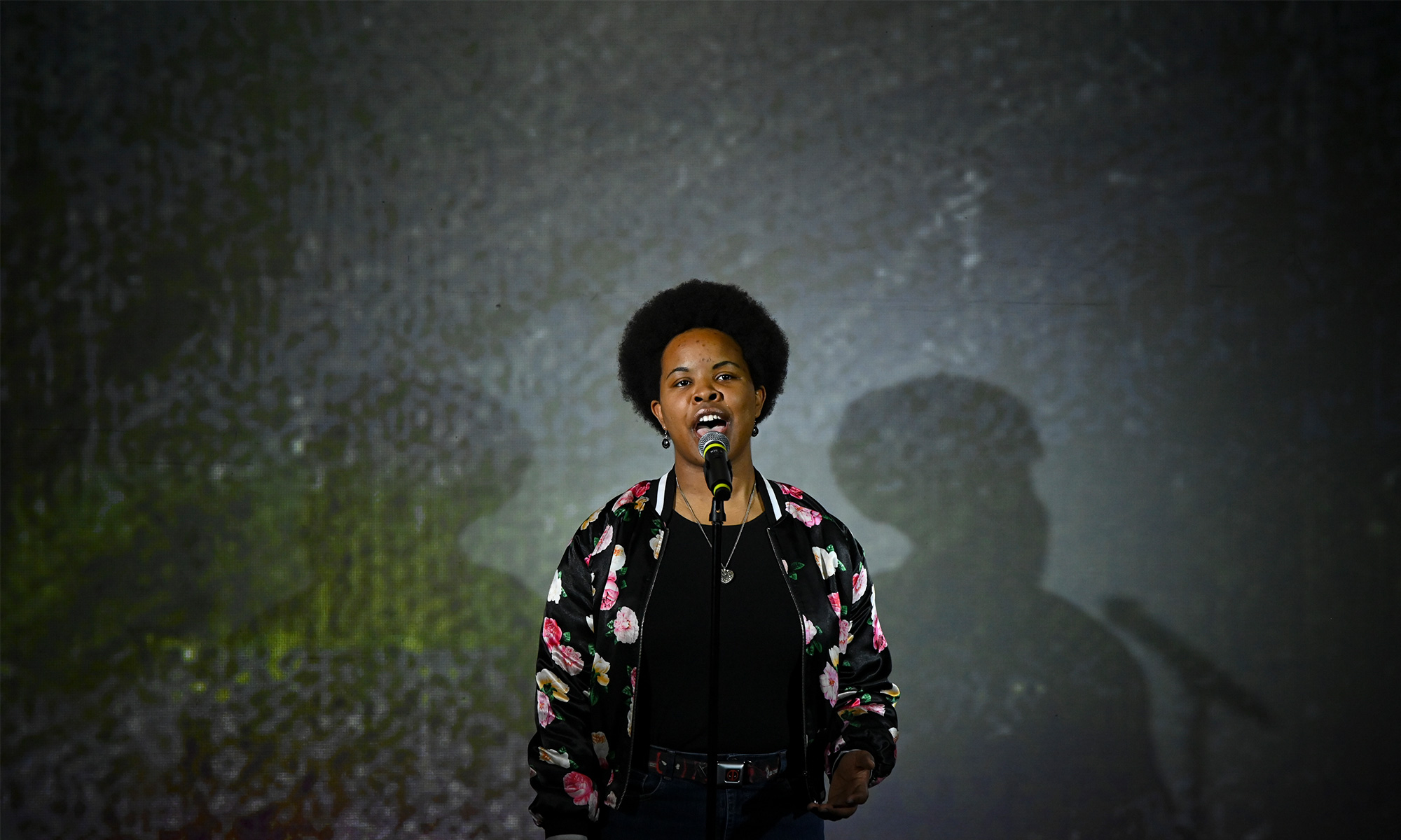 Student talking in front of a microphone with a spotlight on them.