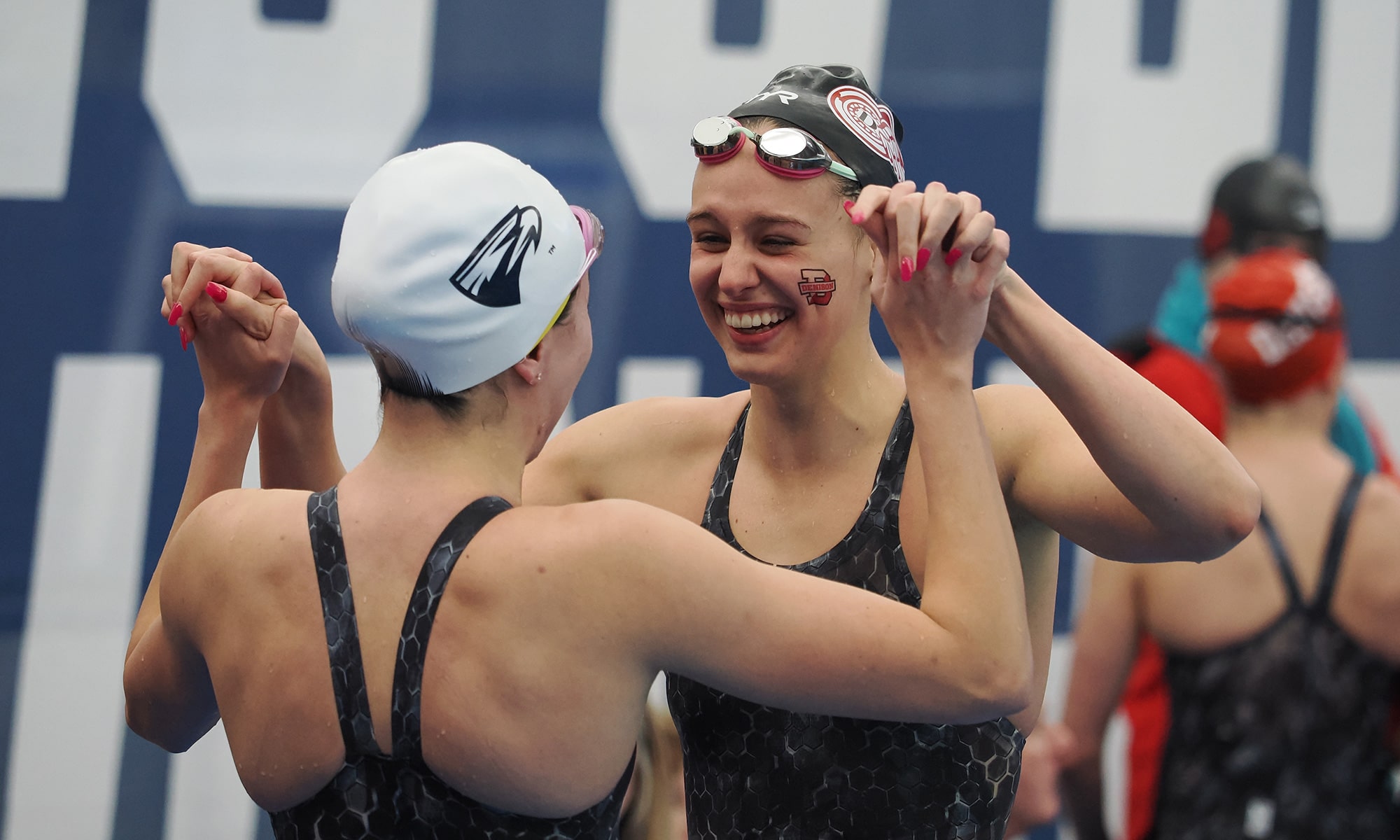 Denison swim & dive team members holding hands and celebrating