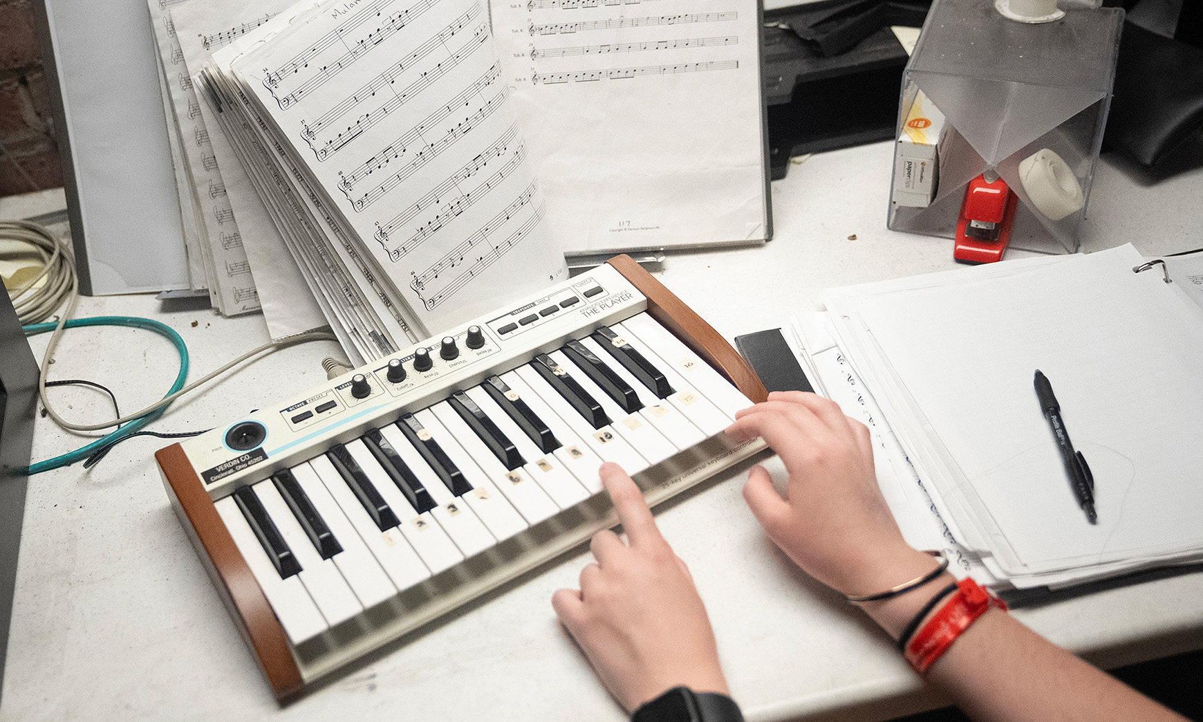 Closeup shot of a small keyboard being played by two hands. 