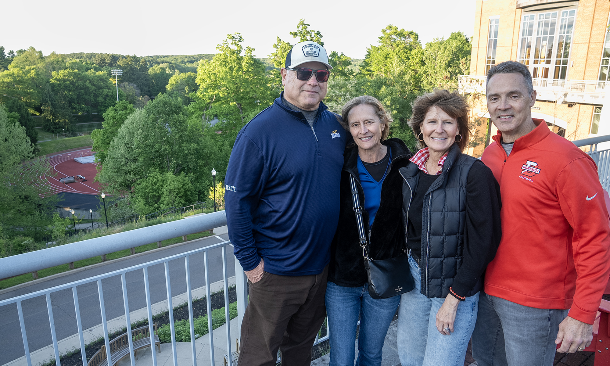 Rick and Lisa Denstorff and Chris and Scott Aiello stand overlooking Denison's football field. 