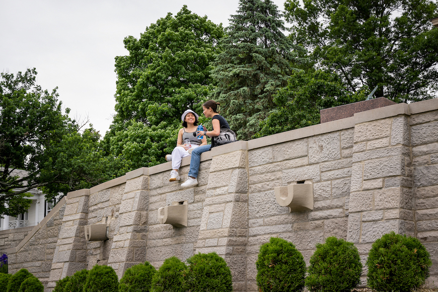 Two students sitting along a wall and talking