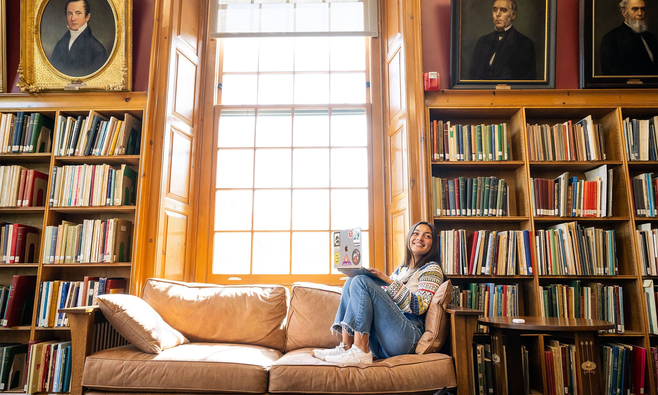 Woman sitting on couch in a library in front of a window