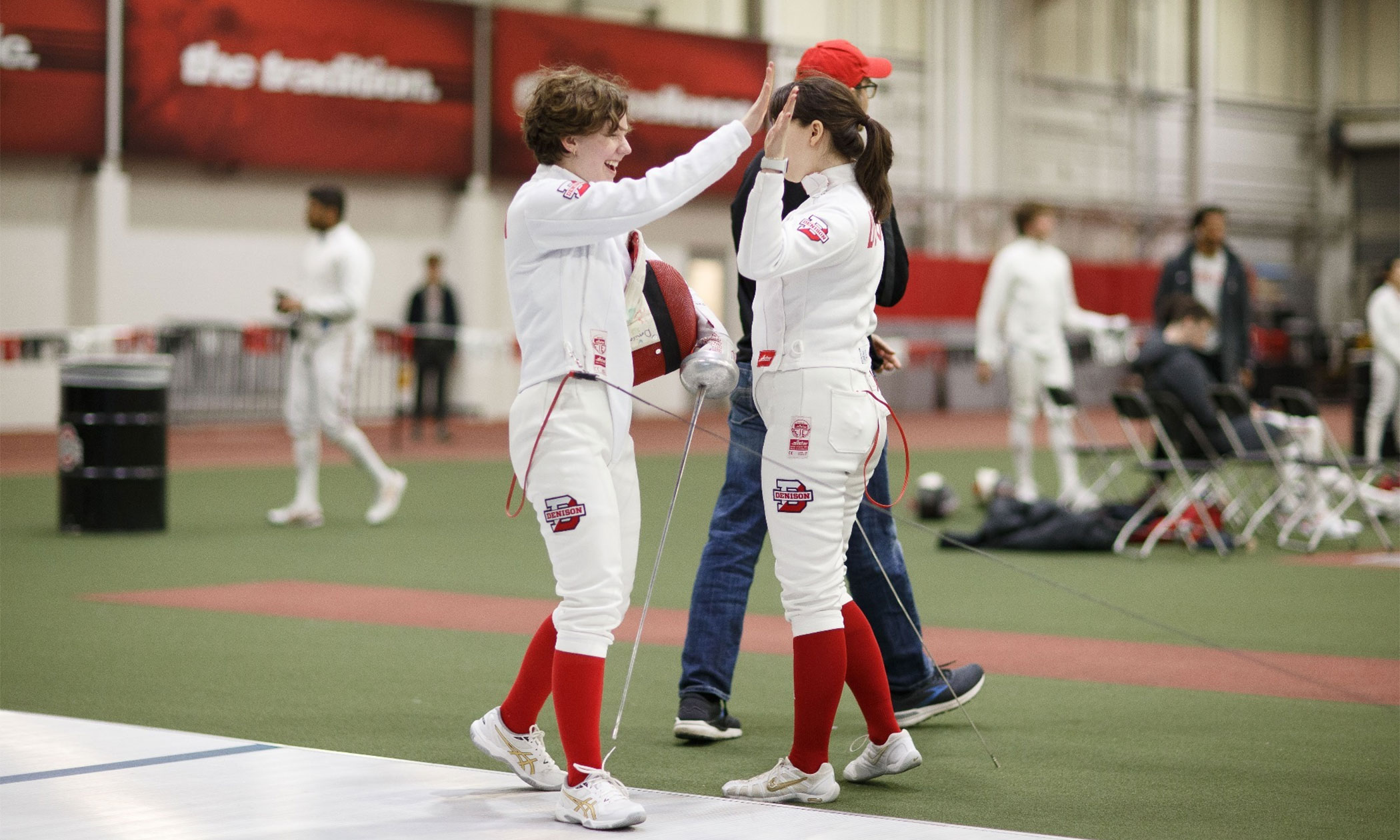 Two people high-fiving in fencing gear