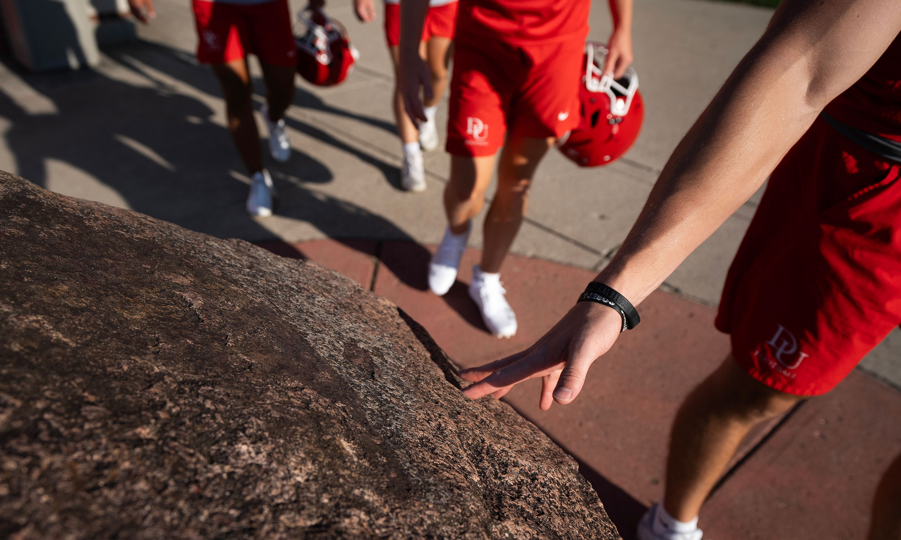 Football player touching a rock