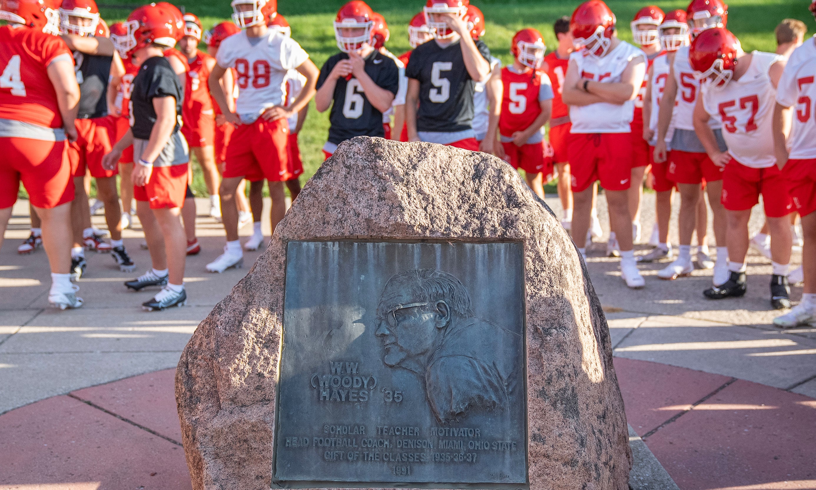 Football team gathering around rock memorial