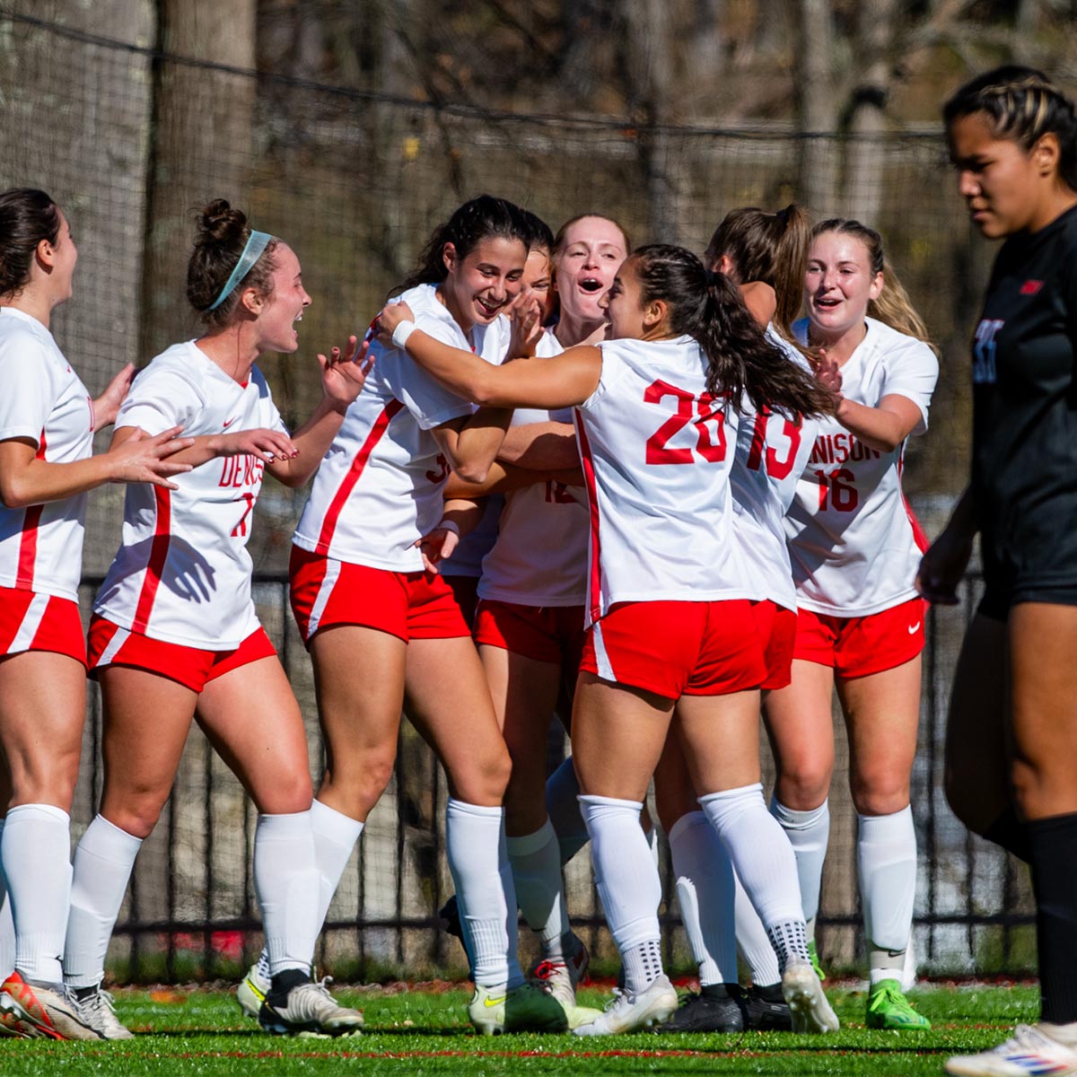 Women's soccer team celebrates on the pitch.