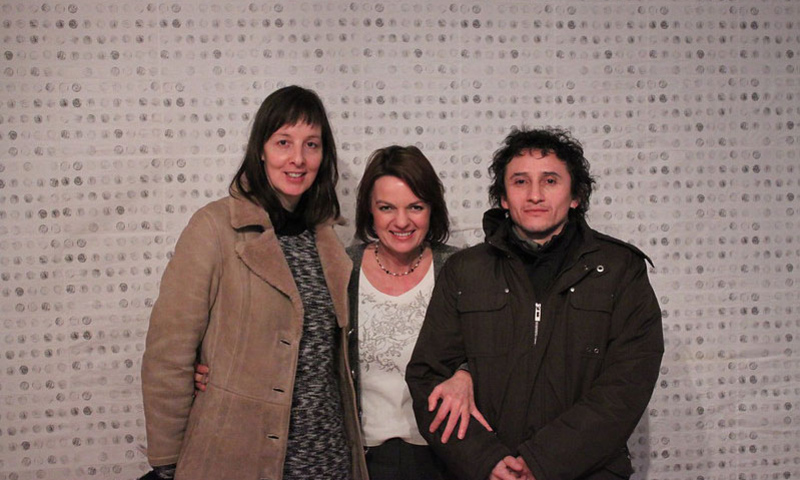 three people smiling in front of wall of dots