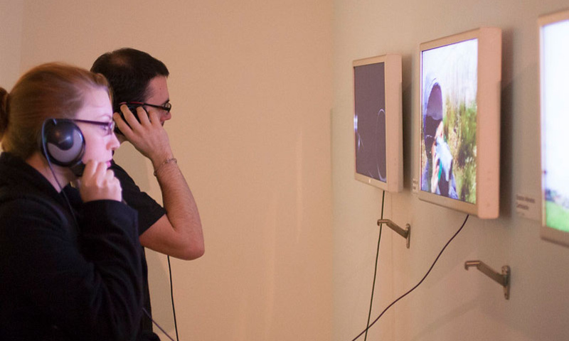 Two people with headphones on watching screens