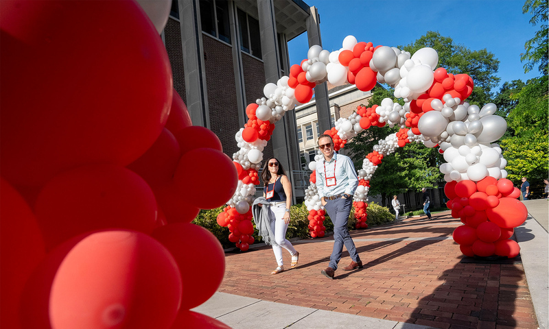 Two people walking beneath colorful balloon arches.