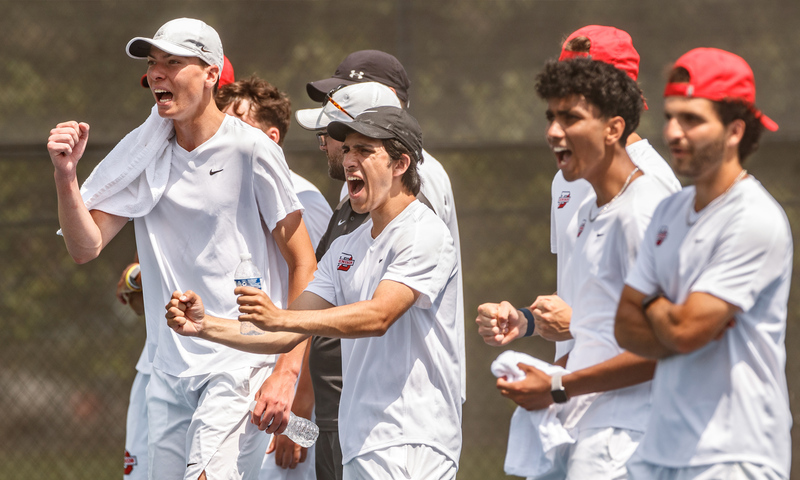 Members of the Denison men's tennis team cheering from the sidelines.