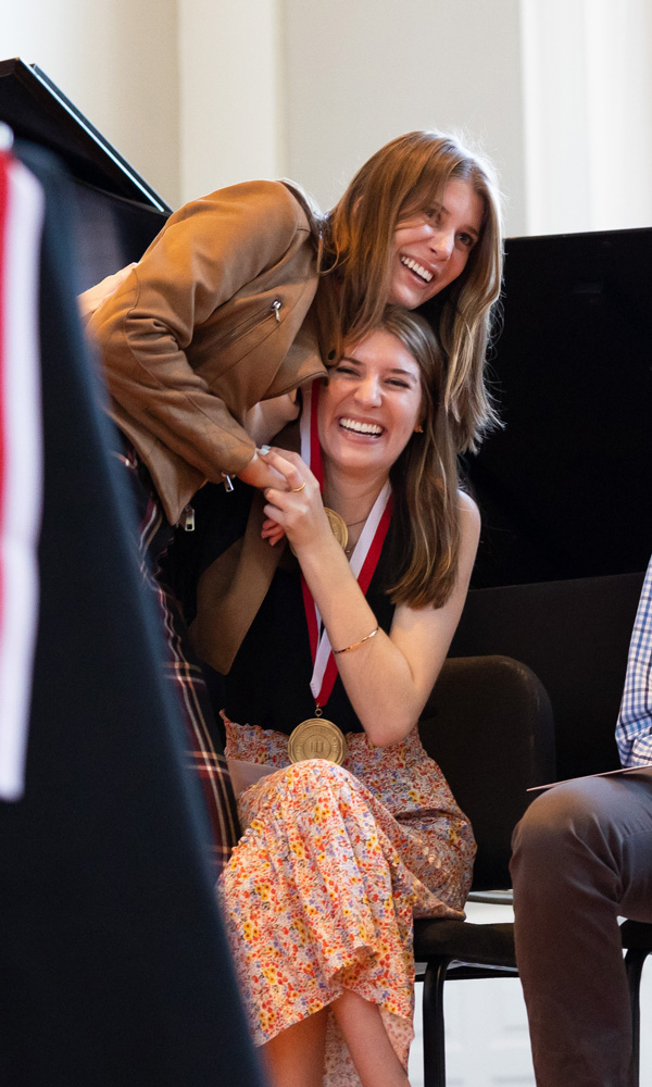 Sophie and Hannah hug on stage seconds after Sophie is announced as a President’s Medal recipient.