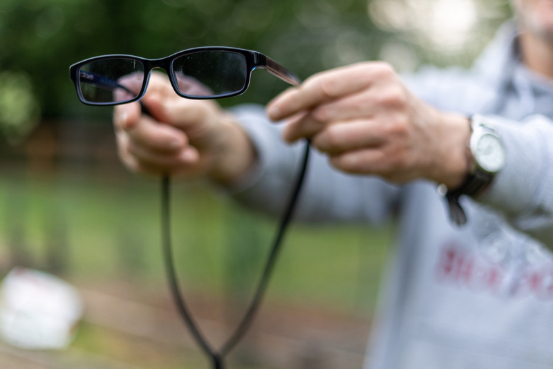 Professor Warren Hauk holds one of the many pairs of tinted glasses that he must keep close at hand to combat headache-inducing bright lights and sunshine. 