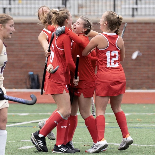 Field hockey team celebrates on the field.