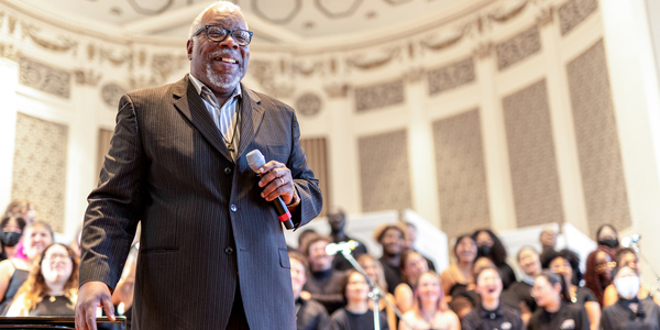 Timothy Carpenter on stage inside Swasey chapel with singers behind him