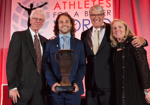 Luke Romick ’16 posing on stage with three presenters of his Wooden Cup Award