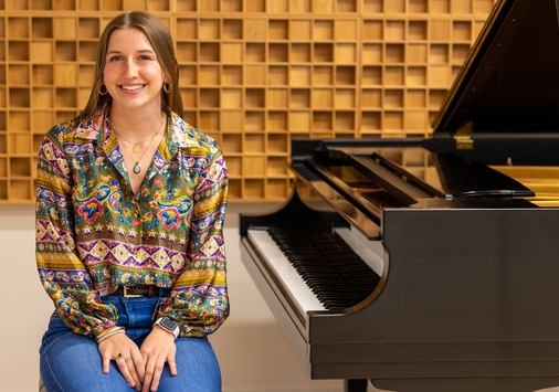 Ellie Blasko '23 sitting next to a piano