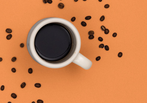 Coffee cup with beans on an orange background