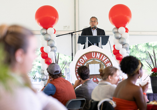 President Adam Weinberg standing at a lectern surrounded by balloons and speaking to an audience. 