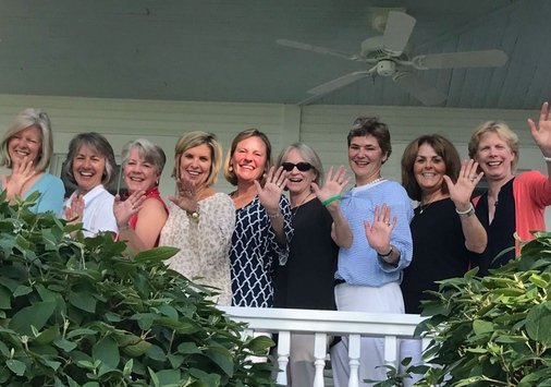 Women posing on porch waving hands