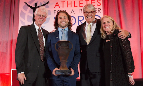 Luke Romick ’16 posing on stage with three presenters of his Wooden Cup Award