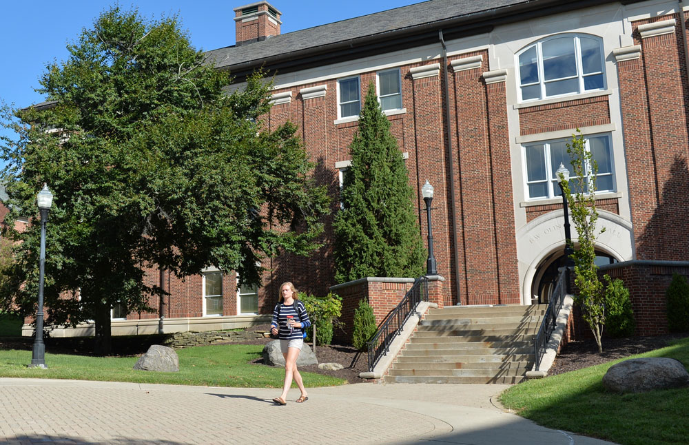 Student walking out of Olin, the building that houses the physics department.