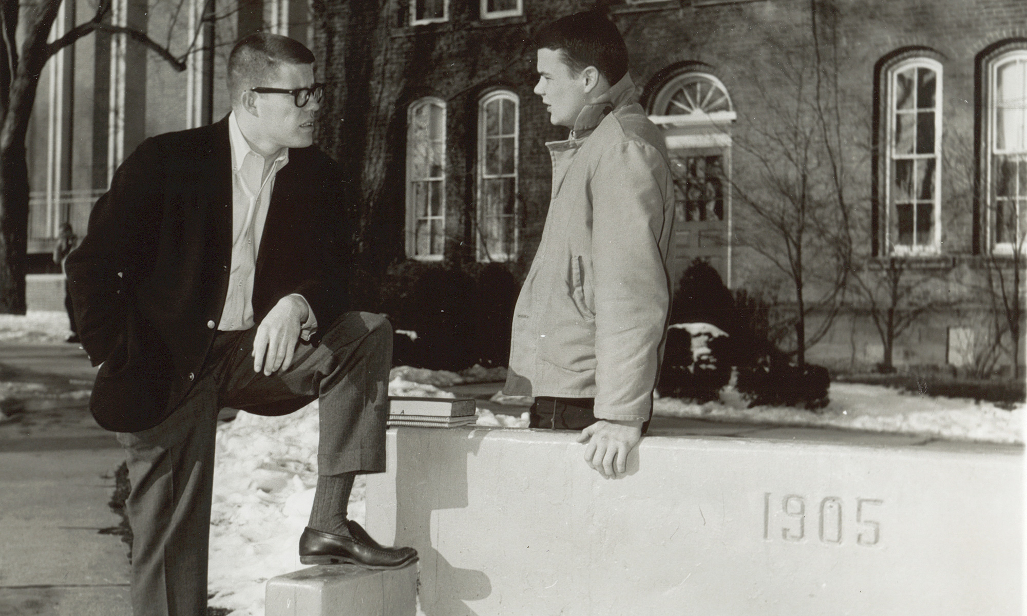 two men standing near the 1905 bench