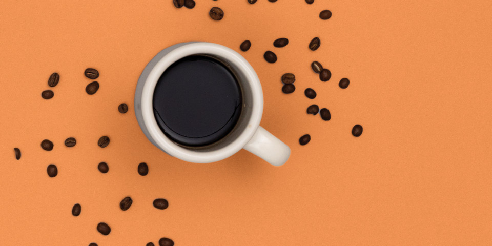 Coffee cup with beans on an orange background