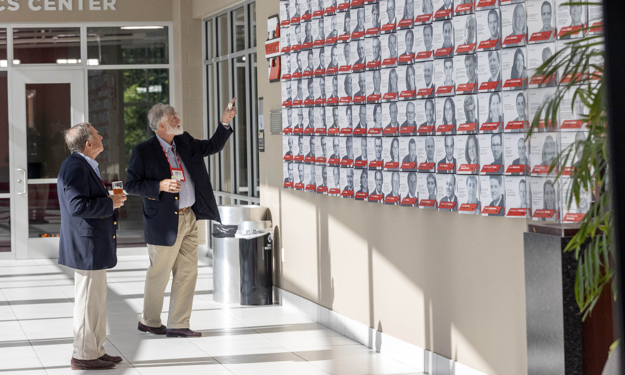 Alumni view photos on the Hall of Fame wall in Mitchell Center